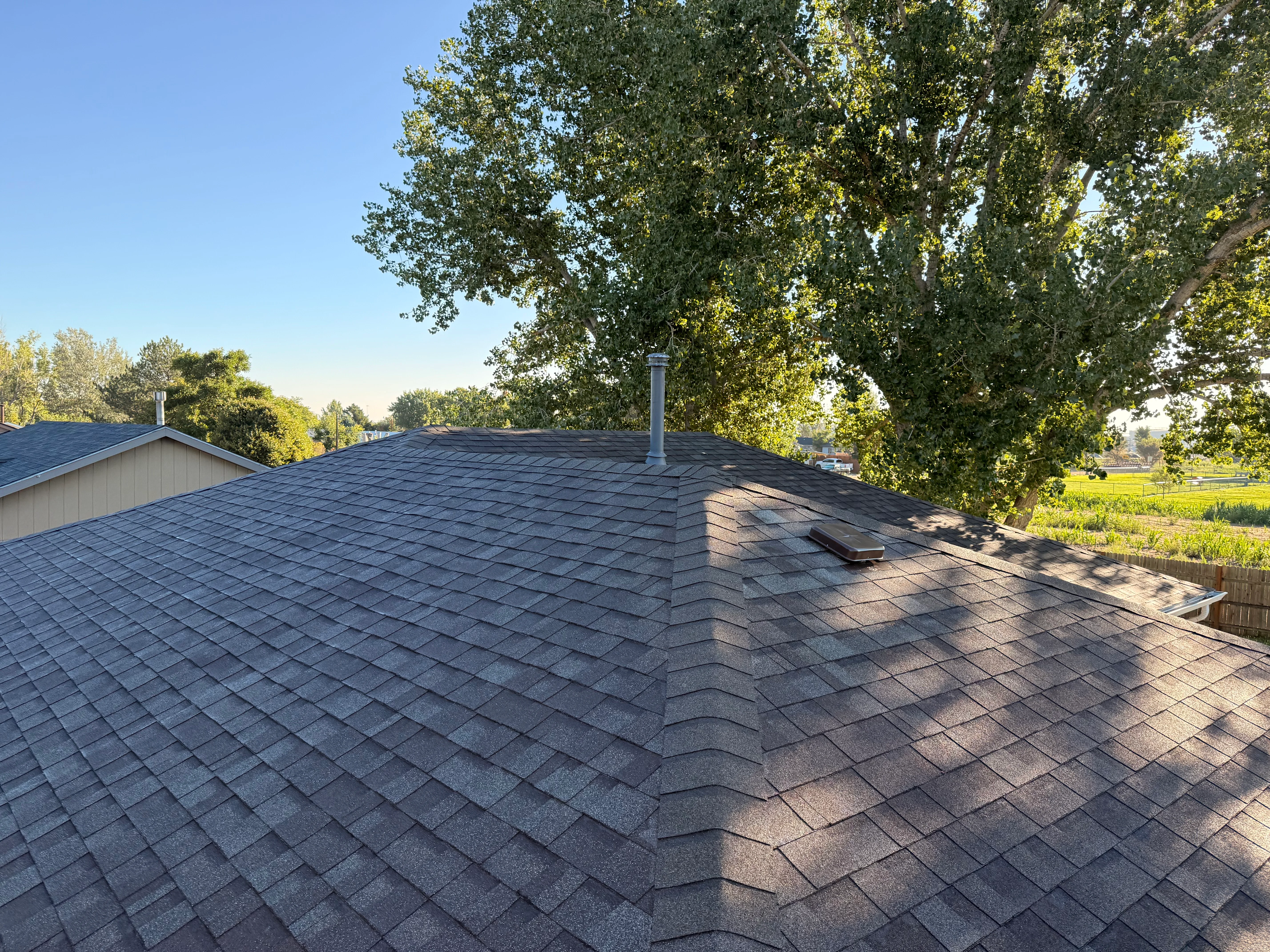 After - Completed architectural shingle roof installation with chimney flashing